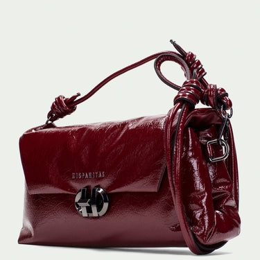 Maroon handbag with decorative handle on a light gray background