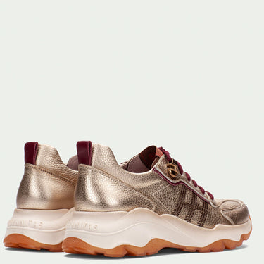 Pair of metallic gold sneakers with brown soles on a light gray background