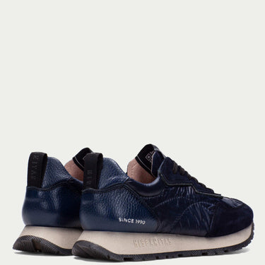 Navy blue sneakers with black accents on a light gray background