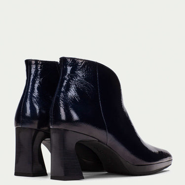 dark navy patent leather ankle boots on a light gray background