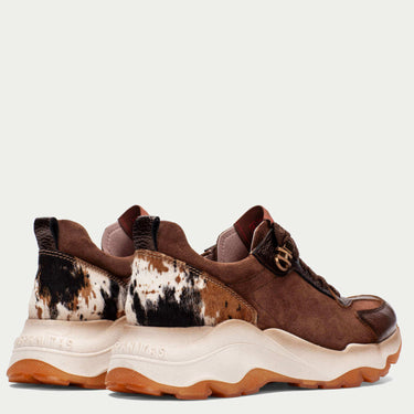 Brown and white sneakers with cow print on a light gray background