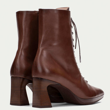Brown leather boots with block heels on a light gray background