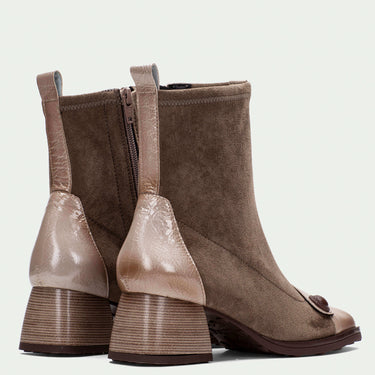 Pair of brown suede ankle boots with decorative elements on a light beige background