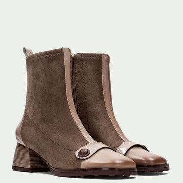 Pair of brown ankle boots with a strap on a light gray background
