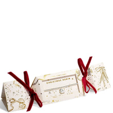 A boxed necklace displayed on a white background. The product is shown in its gift packaging, with a cream-colored box decorated with gold glittery illustrations of bows and stars, tied with red velvet ribbons on both sides.