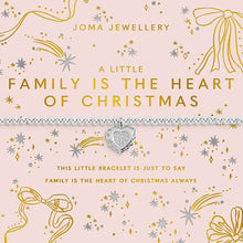 A Joma Jewellery Christmas-themed bracelet on its original pink card packaging. The bracelet is a delicate silver chain with a central silver heart charm engraved with 'I LOVE MY FAMILY'.