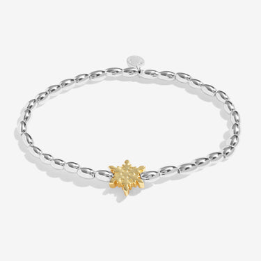 Silver bracelet with a gold flower charm on a white background