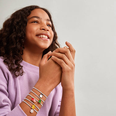 Woman wearing multiple bracelets with colorful charms on a plain background