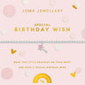 A silver beaded bracelet with a pink star wand charm, presented on a light pink Joma Jewellery gift card with gold text and confetti accents.