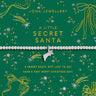 Joma Jewellery Christmas-themed gift card with a silver beaded bracelet across the center, featuring gold and silver holiday illustrations on a dark green background.