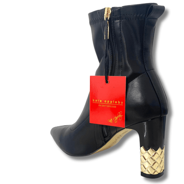 Black ankle boot with gold heel and braided detail, featuring a red tag with 'kate spade new york' branding.