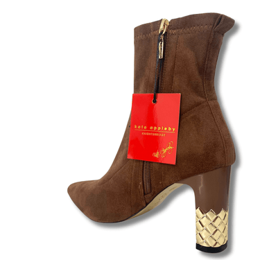Brown ankle boot with gold heel and decorative sole, featuring a red tag on a white background.