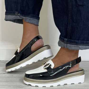 Black and white platform sandals worn with rolled-up jeans on a wooden floor.