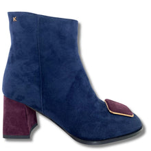 A navy blue suede ankle boot with a block heel, featuring a contrasting deep burgundy suede toe cap and a small gold metal accent on the side.