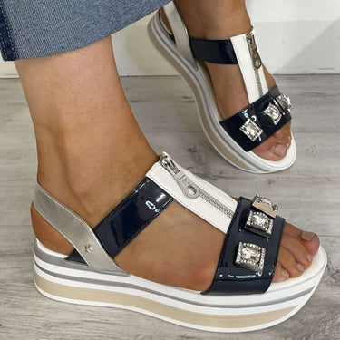 Person wearing platform sandals with a denim skirt on a wooden floor.