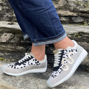Person wearing gray sneakers with black and white patterns on a stone step.