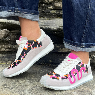 Person wearing colorful sneakers with pink text on a stone surface