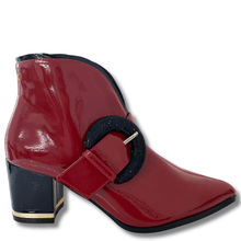 Red patent leather boot with a black buckle on a white background