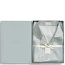 A light blue-gray silk pajama set in a gift box, featuring a matching box cover and a silky pajama top with small silver dot patterns and a cream ribbon tie. The brand name 'MATHIEU LOUIS' is visible on the labels.