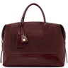 A dark burgundy leather handbag by Katie Loxton, featuring dual top handles, a hanging leather tag with a gold padlock, and gold brand lettering on the lower front, set against a plain white background.