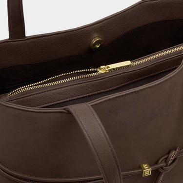 Brown leather handbag with gold zipper and hardware on a light gray background