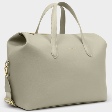 green travel bag with a gold chain on a light gray background