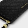 A close-up of a black woven leather zip-around wallet or clutch with gold hardware and gold 'KATIE LOXTON' branding on a light gray background.