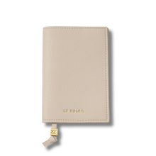 Beige leather passport cover with 'LE SOLEIL' branding on a white background