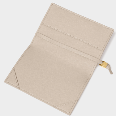 Beige passport cover with a gold clip on a light gray background