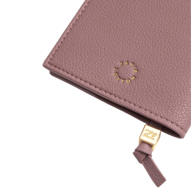 Close-up of a pink leather wallet with a gold tag on a white background