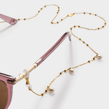 Pink sunglasses with a gold and pearl beaded chain on a light gray background