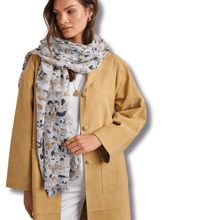 Woman wearing a tan coat and floral scarf on a white background