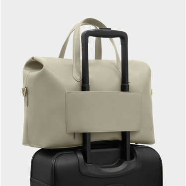 pale green duffel bag with handle on top of a black suitcase