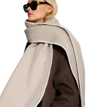 Person wearing a beige scarf and sunglasses on a white background
