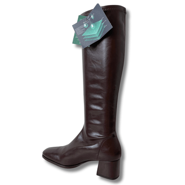 Brown knee-high boot with a tag on a white background