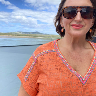 Woman wearing an orange dress with a scenic background