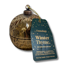 A textured metallic gold spherical candle container with a hanging dark teal tag that reads 'Osmology Winter Thyme' on a white background.