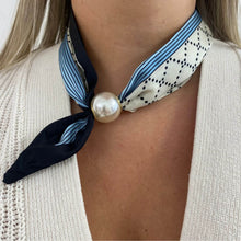 Necklace with a large pearl pendant and striped scarf worn by a person.
