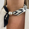Necklace with black and white striped bow and pearl accent on a person wearing a beige sweater.