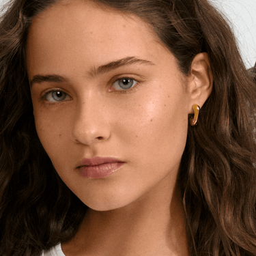 Close-up of a woman with wavy hair wearing a gold earring.