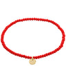 Red beaded bracelet with a gold charm on a white background