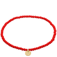 Red beaded bracelet with a gold charm on a white background