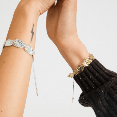 Two bracelets on a person's wrist against a neutral background