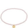 Pink beaded bracelet with a gold charm on a white background