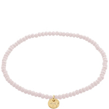 Pink beaded bracelet with a gold charm on a white background