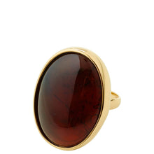 An oval ring featuring a large, polished dark reddish-brown cabochon stone set in a polished yellow gold bezel and band, shown against a plain white background.