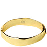 A polished gold bangle bracelet with an irregular, wavy edge, featuring the brand name 'PILGRIM' engraved inside, shown on a plain white background.