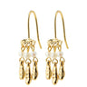 A pair of gold dangle earrings with small white pearl beads and hammered gold charms, shown on a plain white background.