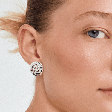 Close-up of a woman wearing a silver floral earring on a white background