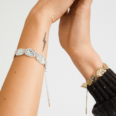 Close-up of a person's arm wearing two bracelets on a light background